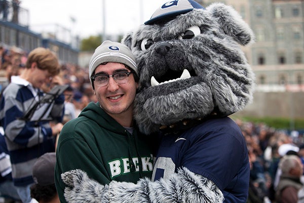 photo of the Georgetown Mascot embracing with a student at a game. 